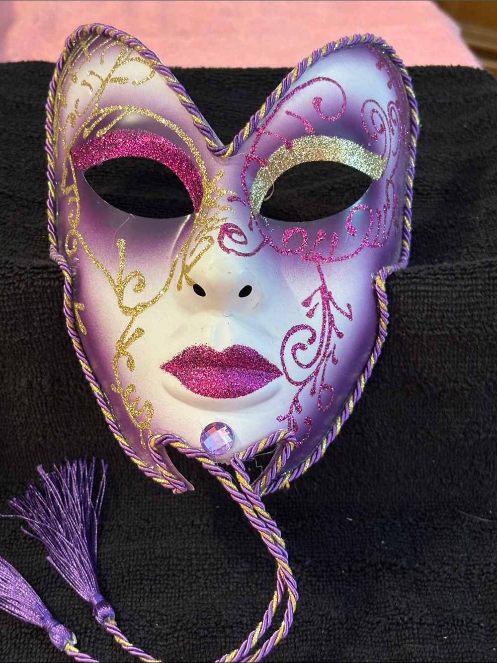 Venetian-style masquerade mask decorated with glitter, tassels,central gem.